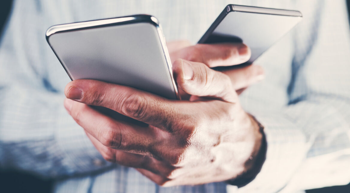 Ein Mann hält in jeder Hand ein Smartphone.