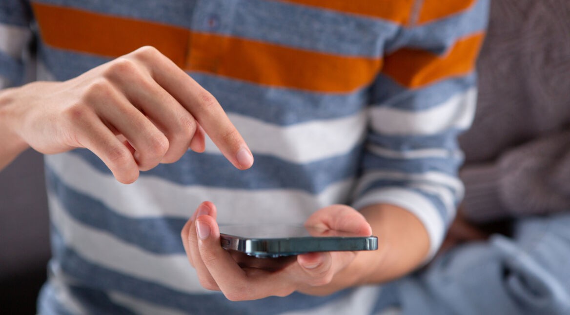 Ein Mann hält ein iPhone in der Hand und bedient es mit dem Zeigefinger.