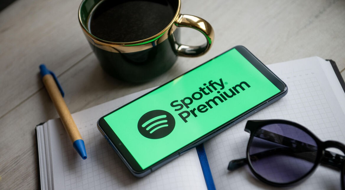 Ein Smartphone mit dem "Spotify Premium"-Logo liegt auf einem Schreibtisch zwischen anderen Utensilien.