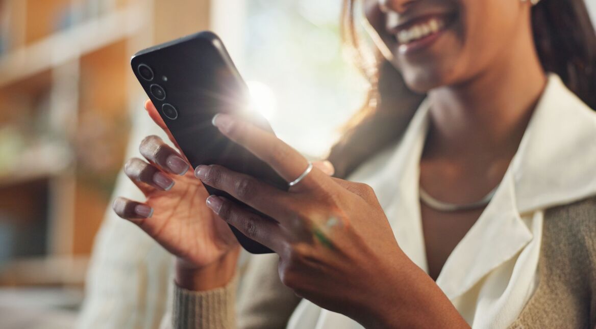 Frau schaut lächelnd auf ihr Samsung-Handy.