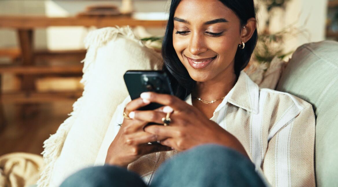 Frau schaut lächelnd auf ihr Smartphone.
