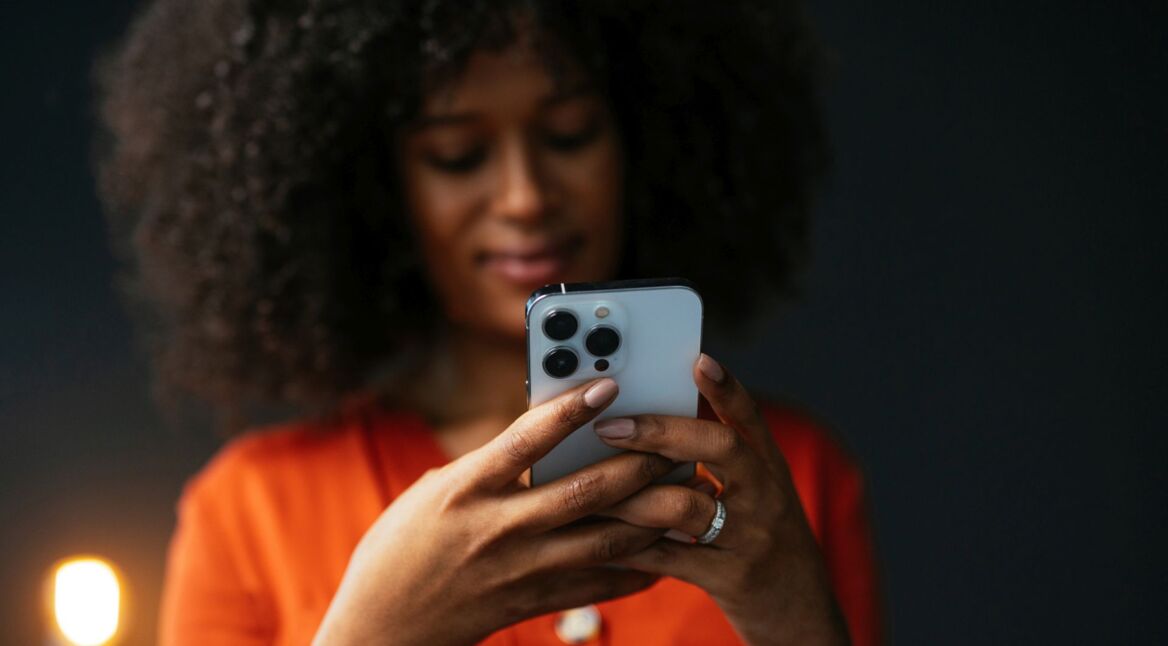 Schwarze Frau hält ein iPhone in den Händen.