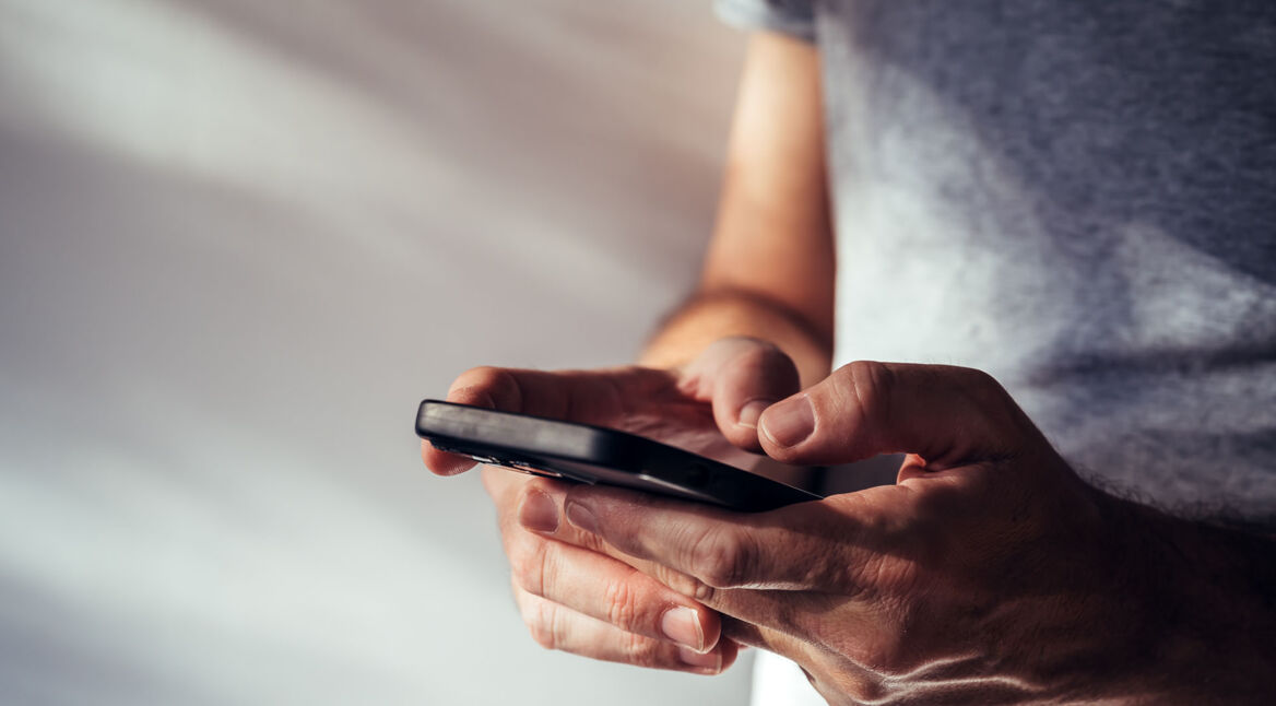 Ein Mann hält ein Smartphone in seinen Händen.