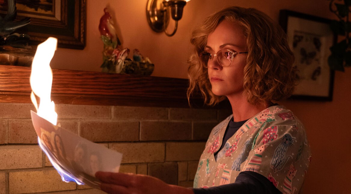 Paramount+ beste serien zeigt in dieser Szene Christina Ricci als Misty aus der Serie Yellowjackets. Sie steht vor einem Kamin und hält ein brennendes Foto in der Hand.