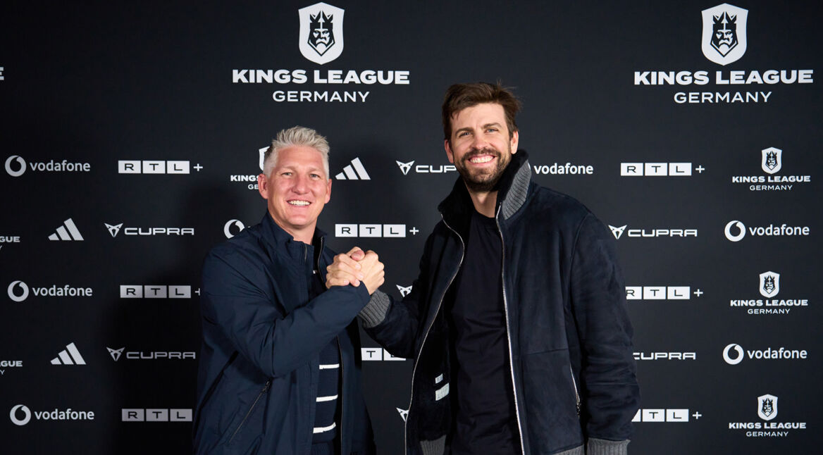 Auf dem Bild zur Kings League Germany stehen die ehemaligen Fußballstars Bastian Schweinsteiger und Gerard Piqué vor einer Sponsorenwand der Kings League Germany. Beide lächeln in die Kamera und geben sich sportlich die Hand. Die Szene wirkt freundschaftlich und professionell, passend zum sportlichen Auftakt des neuen Fußballformats in Deutschland.