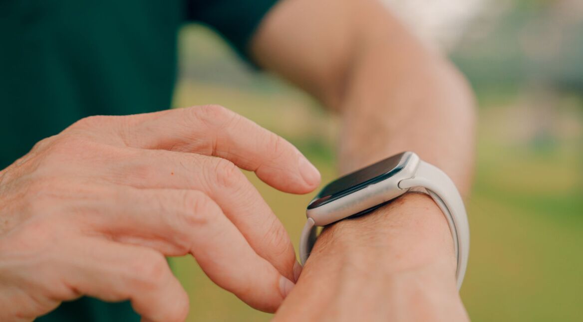Frau tippt auf die Apple Watch an ihrem Handgelenk.