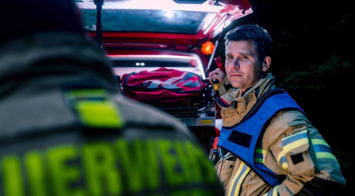 Berufsfeuerwehrmann steht vor Mehrzweckfahrzeug