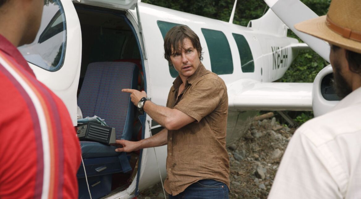 Tom Cruise als Barry Seal steht vor einem offenen Flugzeug.