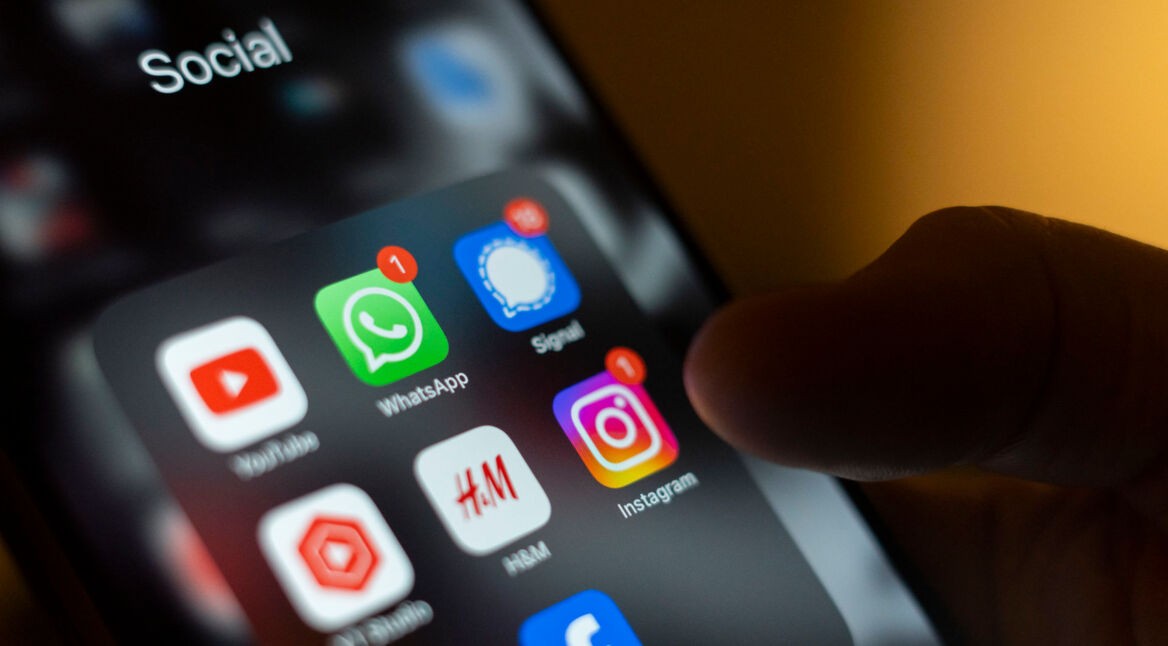 Ein Handydisplay zeigt die Icons verschiedener Apps, darunter WhatsApp und Signal.