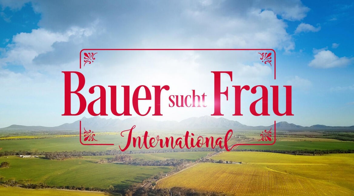 Offizielles Pressebild zur RTL-Sendung „Bauer sucht Frau international Staffel 7“ mit dem prominent platzierten Logo in roter Schrift. Im Hintergrund ist eine weite, sonnige Landschaft mit Feldern, Wiesen und Bergen unter einem teils bewölkten Himmel zu sehen. Das Bild vermittelt eine romantische, naturnahe Stimmung und bewirbt die internationale Ausgabe der beliebten Kuppelshow.