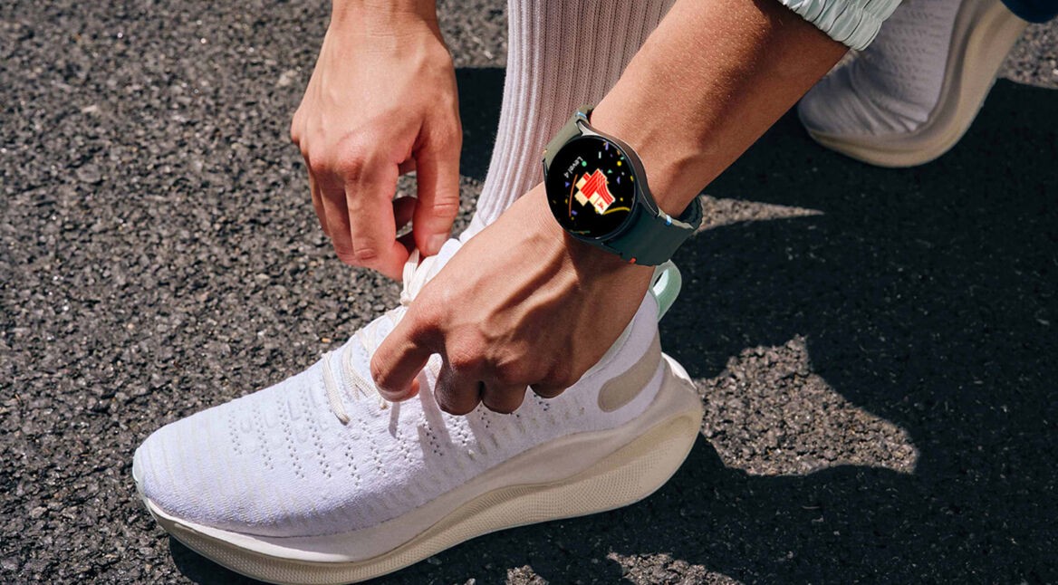 Mann mit Galaxy Watch am Arm bindet seine Schuhe zu.