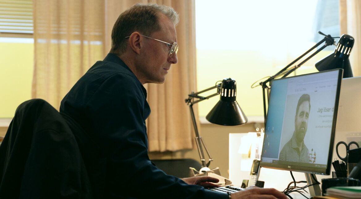 Peter Eggers sitzt in einer Szene von "Genombrottet" vor dem Computer.