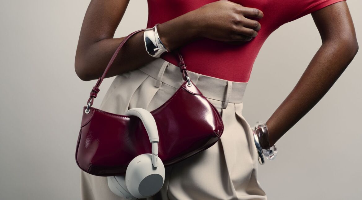 Frau trägt Sony-Kopfhörer über ihrer Handtasche.