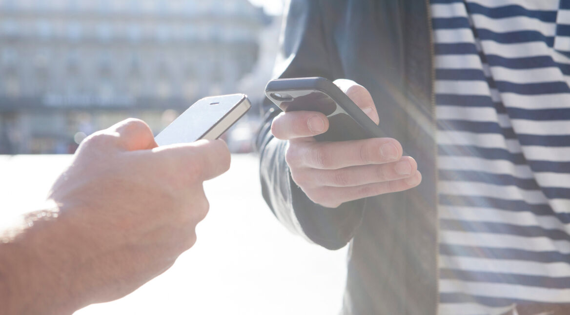 Zwei Hände, die zwei Smartphones aneinanderhalten.