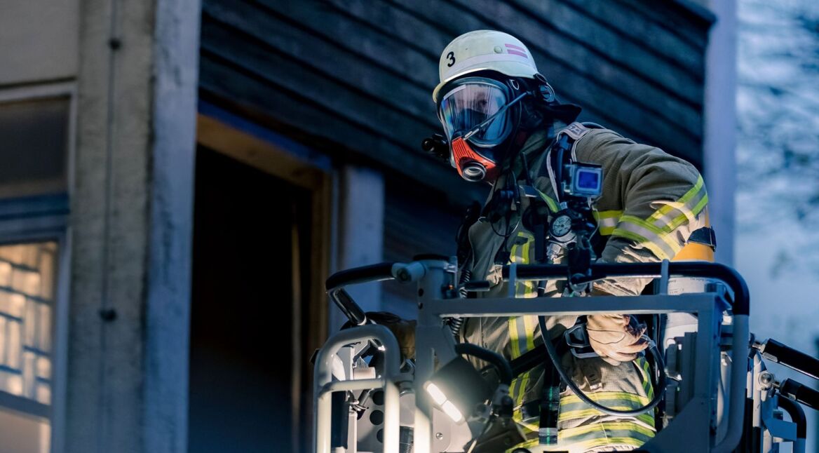 Ein Feuerwehrmann in "Feuer und Flamme" bei einem Einsatz auf der Drehleiter.
