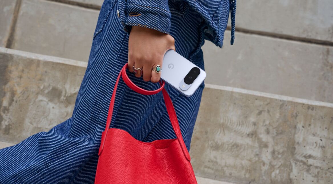 Eine Person hält das Pixel 10 und eine rote Handtasche in der Hand.