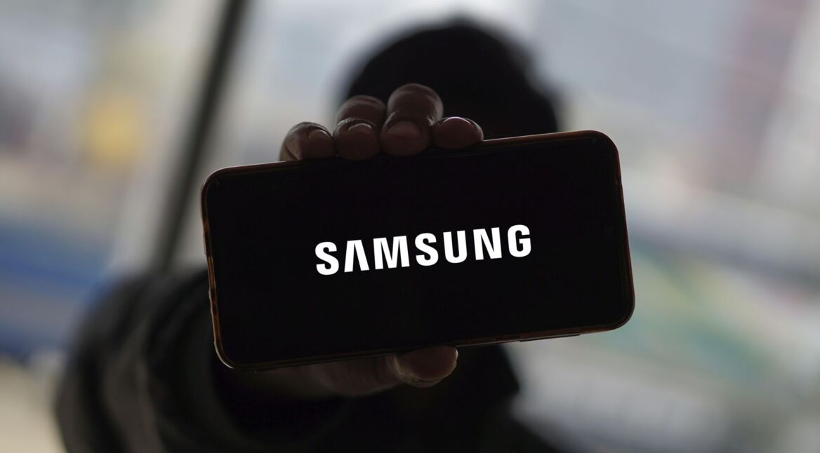 Mann hält Smartphone hoch, auf dem das Samsung-Logo zu sehen ist.
