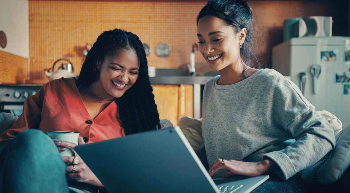 FRITZ!Box 6660 Cable WLAN Priobleme: Zwei Frauen sitzen locker und lachend vor einem Laptop.