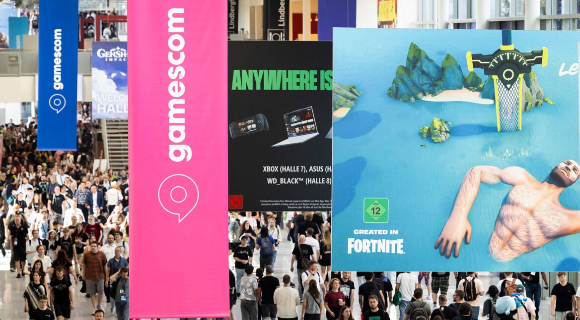 Auf dem Bild von der gamescom 2025 sind viele Besucher:innen auf dem Messegelände zu sehen. Über der Menge hängen große Banner mit dem Logo der Messe sowie Werbeplakate zu bekannten Videospielen.
