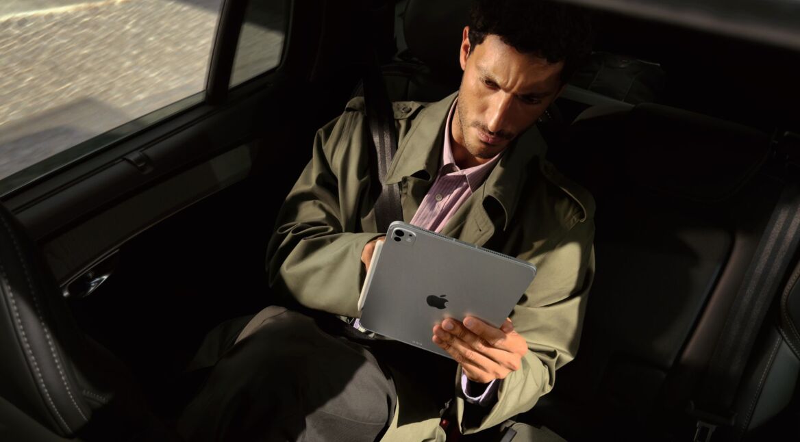 Mann sitzt im Auto und schaut auf das iPad Pro in seinen Händen.
