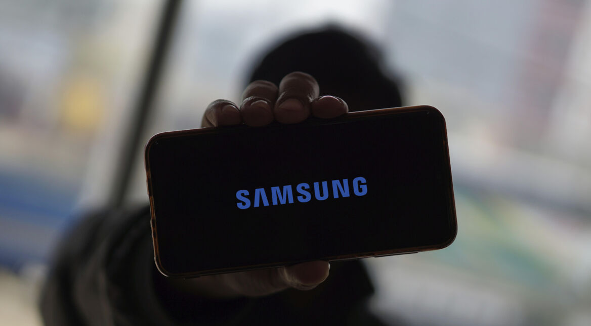 Eine Hand hält ein Smartphone hoch, auf dem das Samsung-Logo zu sehen ist.