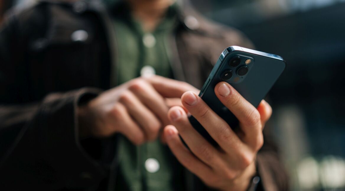 Mann tippt auf ein iPhone.