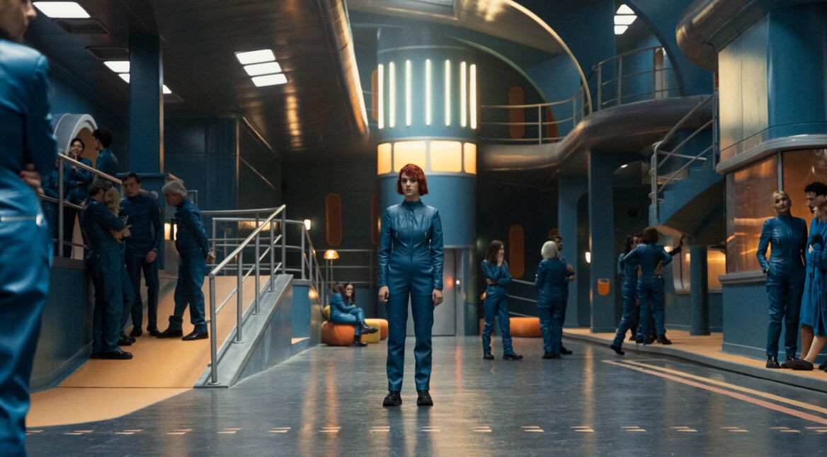 Asia (Alicia Falcó) steht im Bunker, im Hintergrund weitere Bewohner.