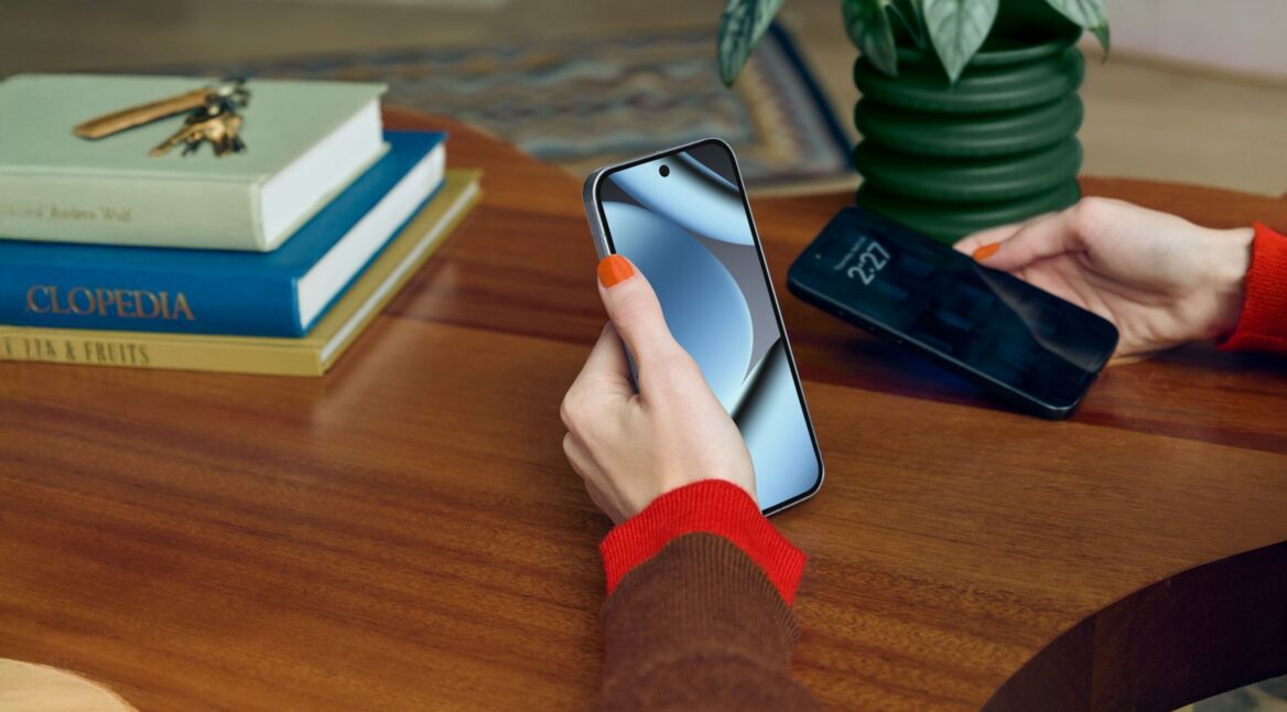 Eine Hand hält das Google Pixel 10 Pro, im Hintergrund ein dunkler Holzschreibtisch mit Büchern.