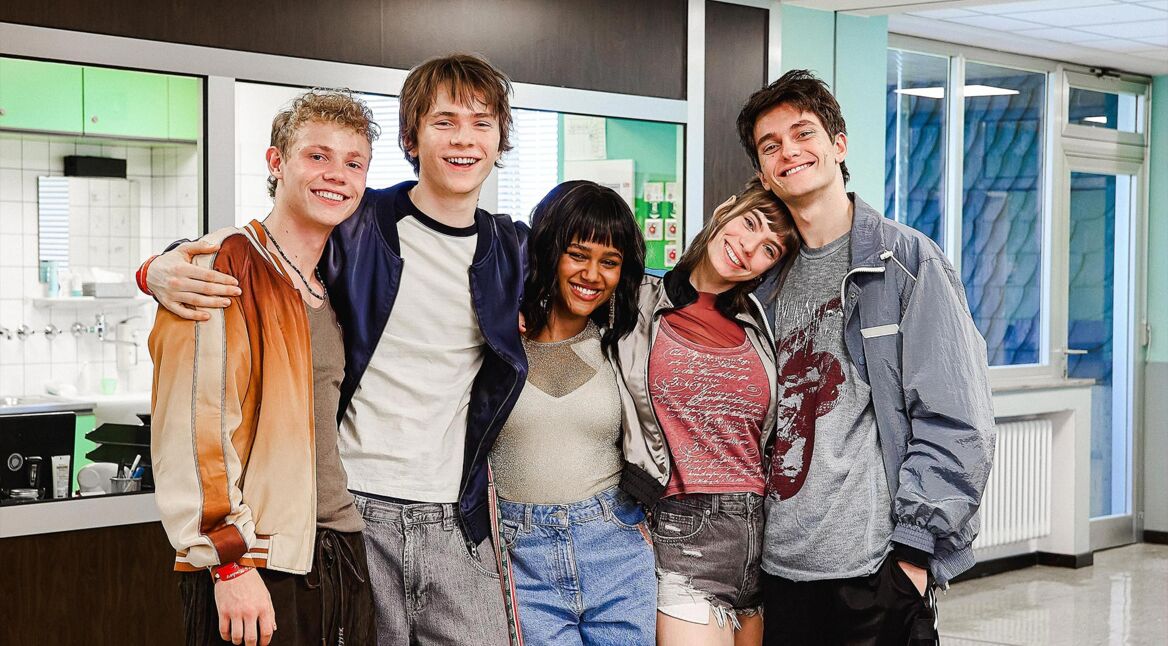 Auf dem Bild in dem Artikel zu Club der roten Bänder – Die neue Generation posieren fünf junge Darsteller:innen in einem Flur.