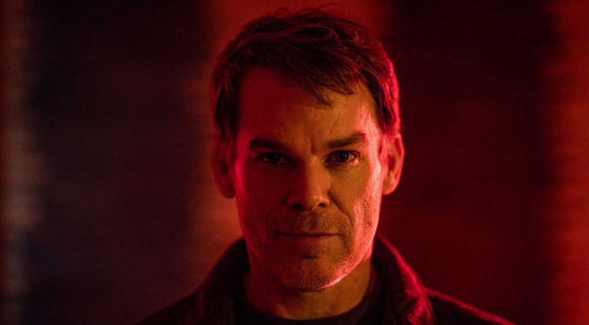 Auf dem Bild zu Dexter: Wiedererwachen ist Dexter Morgan zu sehen, gespielt von Michael C. Hall. Er blickt ernst und direkt in die Kamera, umgeben von dramatischem Rotlicht, das eine düstere und spannungsgeladene Stimmung erzeugt. Das Bild vermittelt eine intensive Atmosphäre, passend zur düsteren Serie.