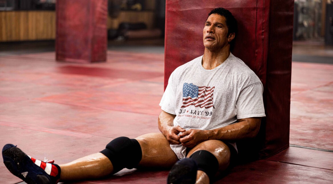 Dwayne Johnson in The Smashing Machine: Ein muskulöser Mann sitzt durchgeschwitzt und erschöpft auf dem Boden einer Trainingshalle.