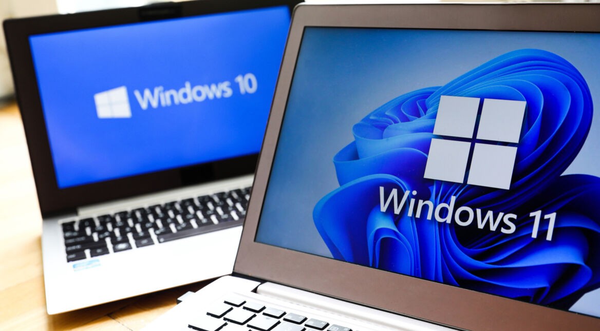 Zwei Notebooks, das im Hintergrund mit dem Logo von Windows 10, das im Vordergrund mit dem Logo von Windows 11