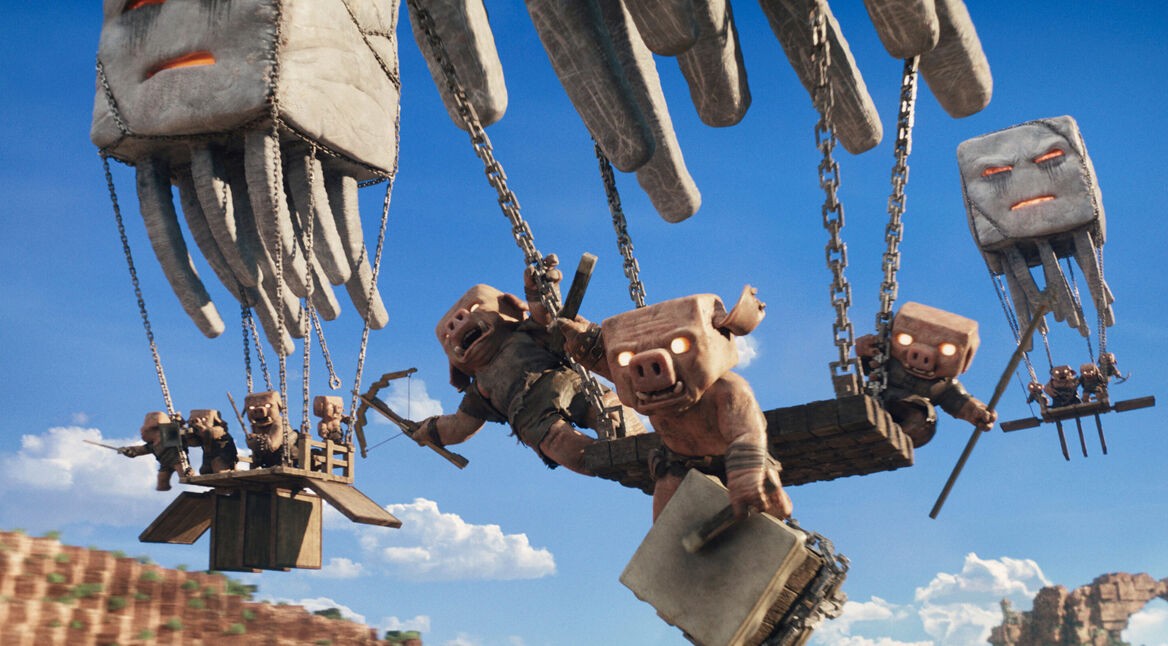 Auf dem Bild in dem Artikel zu „Ein Minecraft Film 2“ sind fliegende Kreaturen zu sehen, die hölzerne Plattformen mit mehreren Piglins durch die Luft tragen.