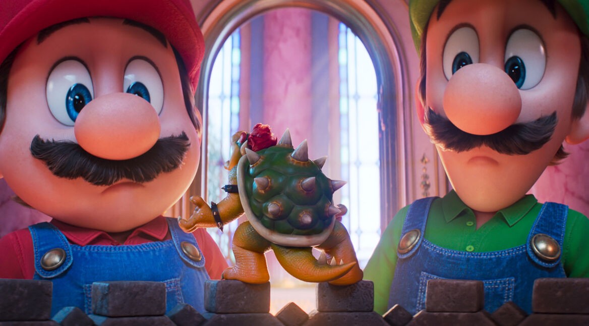 In dieser Szene aus Der Super Mario Galaxy Film stehen Mario, gesprochen von Chris Pratt, und Luigi, gesprochen von Charlie Day, vor einer kleinen Bowser-Figur, deren Filmversion von Jack Black gesprochen wird. Beide Brüder blicken überrascht auf das Mini-Modell, während warmes Schlosslicht durch hohe Fenster fällt und die Situation humorvoll wirken lässt.