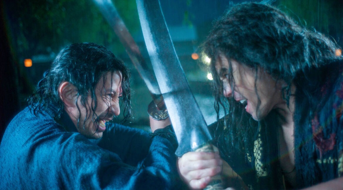 Szenenbild aus der Serie Last Samurai Standing: Zwei Kämpfer mit nassen Haaren liefern sich im strömenden Regen einen intensiven Schwertkampf, ihre Klingen blockieren sich in einem kraftvollen Schlagabtausch.