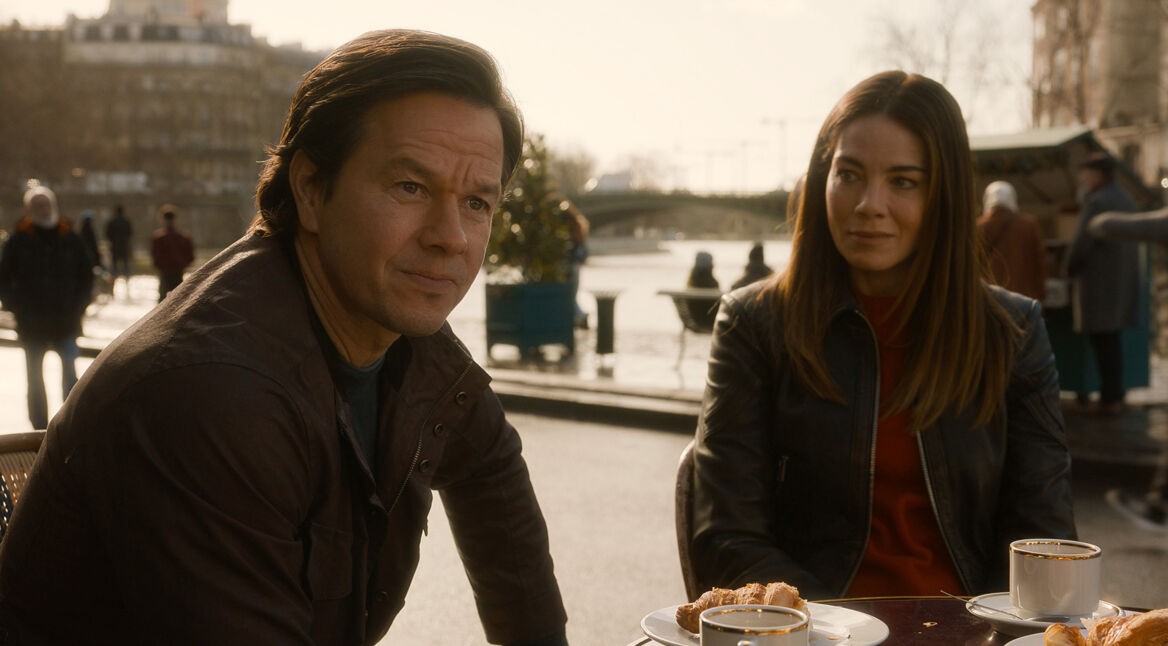 Auf dem Bild in dem Artikel zum „The Family Plan 2-Ende erklärt“ sitzen Dan und Jessica an einem Café-Tisch. Gespielt werden die Charaktere von Mark Wahlberg und Michelle Monaghan.