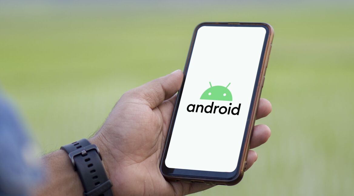 Ein Mann hält Smartphone hoch, auf dem das Android-Logo zu sehen ist