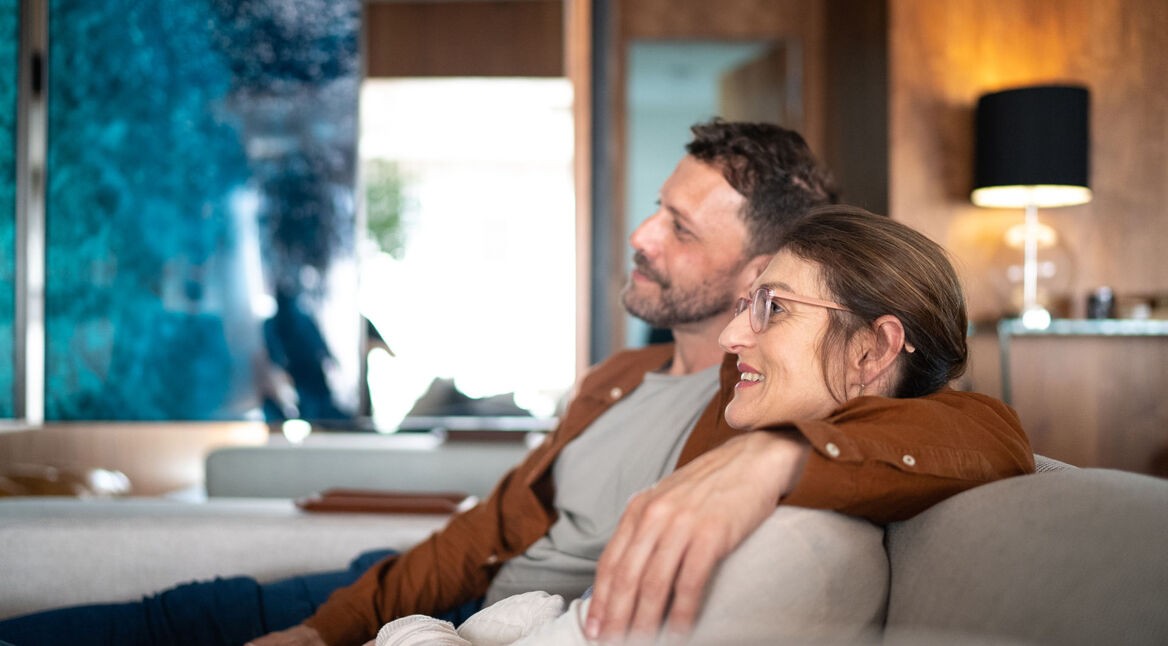 Ein Paar sitzt auf der Couch und schaut Tv.