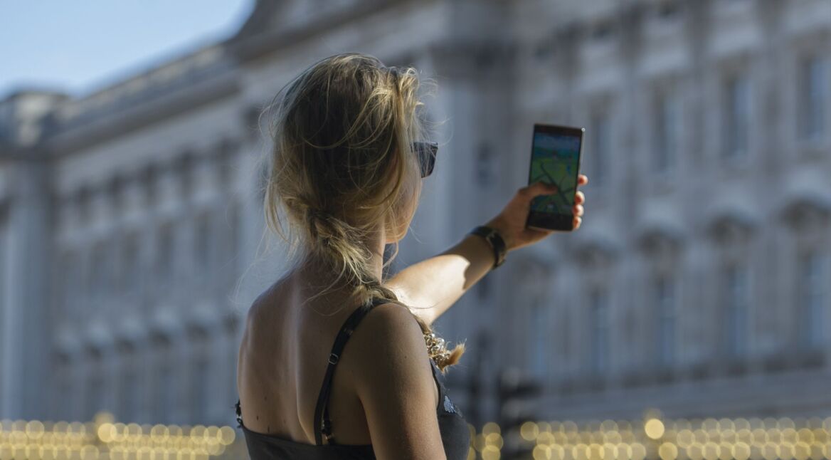 Eine junge Frau hält ihr Handy hoch, während sie vor dem Buckingham Palast in London "Pokémon GO" spielt.