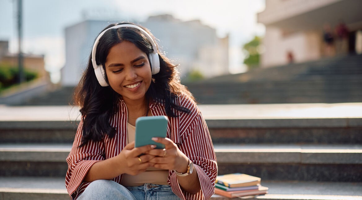 Auf dem Bild in dem Artikel zu den besten Hörbüchern 2025 laut BookBeat ist eine junge Frau mit langen dunklen Haaren mit Kopfhörern zu sehen.