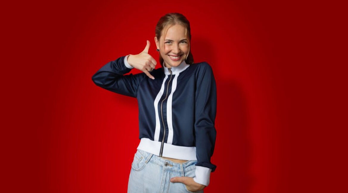 Auf dem Bild in dem Artikel zu den CallYa-Jahrespaketen und den Upgrades ist eine junge Frau vor rotem Hintergrund zu sehen. Sie trägt eine dunkelblaue Jacke und eine helle Jeans.