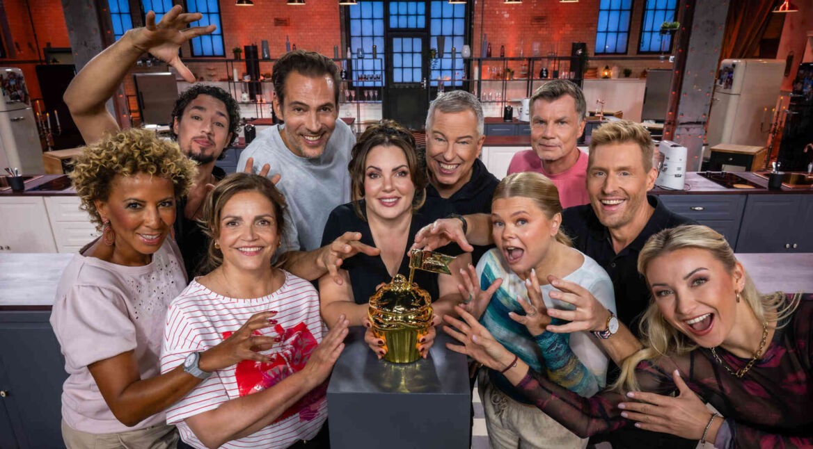 Die Teilnehmer der 10. Staffel "Promibacken" stehen rund um die goldene Sieger-Trophäe.