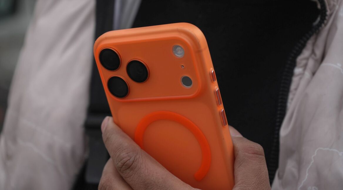 Mann hält das iPhone 17 Pro Max in der Farbe Cosmic Orange in seiner Hand.