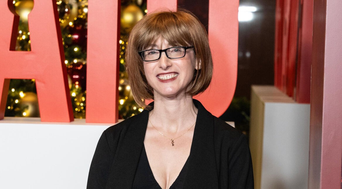 Auf dem Bild ist Autorin Freida McFadden bei der Premiere von „The Housemaid“ in New York zu sehen. Sie steht lächelnd vor einer festlich beleuchteten Kulisse mit großen roten Buchstaben, trägt ein schwarzes Outfit und eine Brille. Ihre kurze, rötliche Bob-Frisur rahmt ihr Gesicht. Das Bild dient symbolisch für die Freida McFadden-Reihenfolge.