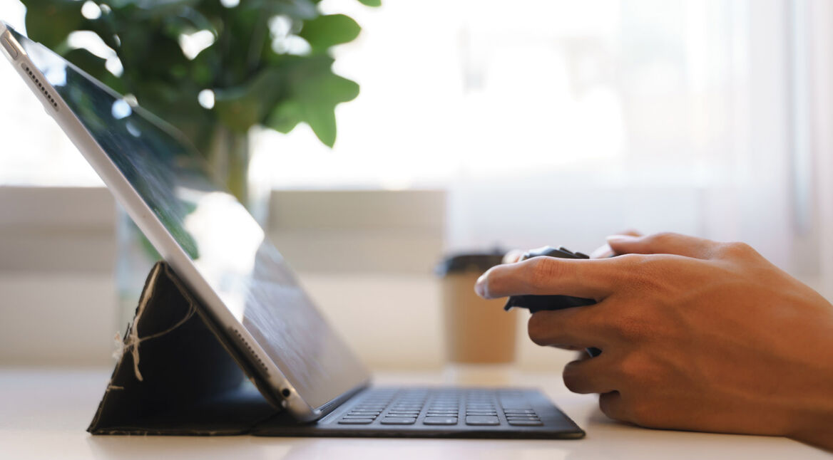 Eine Person spielt mit einem Controller an einem Tablet.