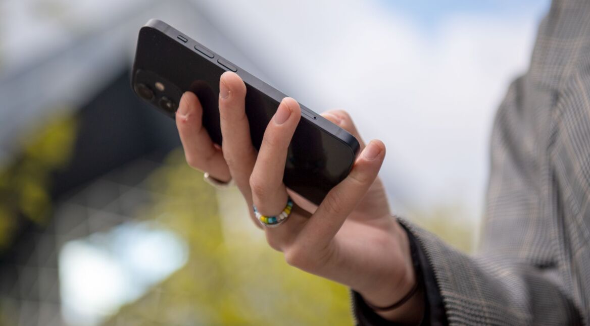 Frau hält schwarzes iPhone in der Hand.