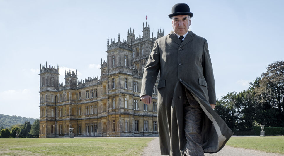 Mann mit Hut und schwingendem Mantel entfernt sich von Downton Abbey. Foto: Universal