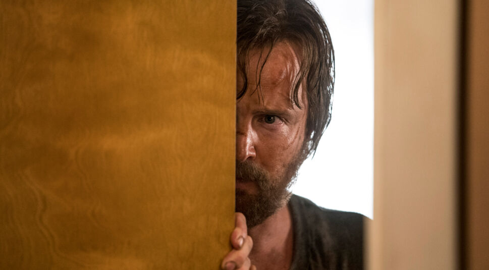 Der geschundene Jesse Pinkman blickt in El Camino: Ein "Breaking Bad"-Film hinter einer Tür hervor. Foto: Netflix