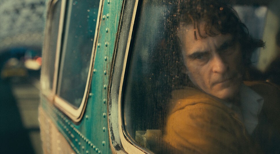 Joaquin Phoenix fährt in Joker im Bus und blickt unglücklich aus dem Fenster. Foto: Warner Bros.