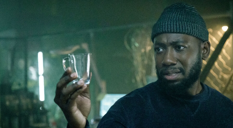 Mann mit Mütze hält in Bloodshot eine Tasse in der Hand